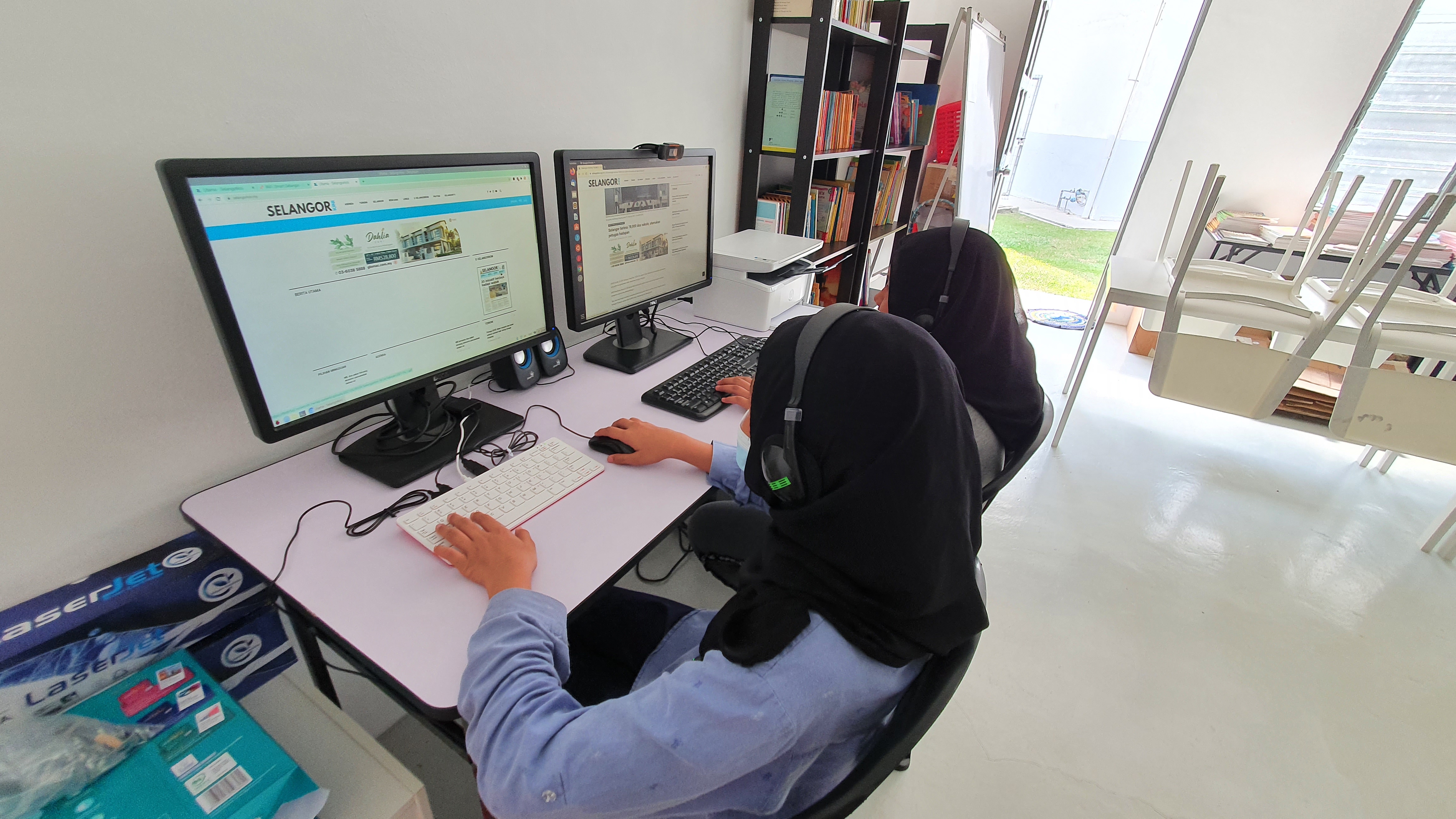 Two students using community library facilities to access Internet